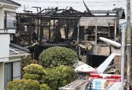 The tail section of a crashed light plane (bottom R) and burning house are seen after the plane went down in a residential area and burst into flames, in Chofu, outskirt of Tokyo, July 26, 2015. (REUTERS/Yuya Shino)