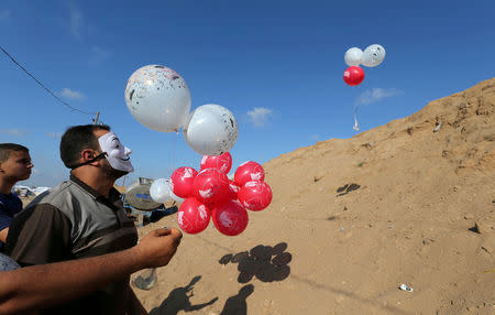 FILE PHOTO: Palestinians fly balloons loaded with flammable material to be thrown at the Israeli side, near the Israel-Gaza border in the central Gaza Strip, June 4, 2018. REUTERS/Ibraheem Abu Mustafa