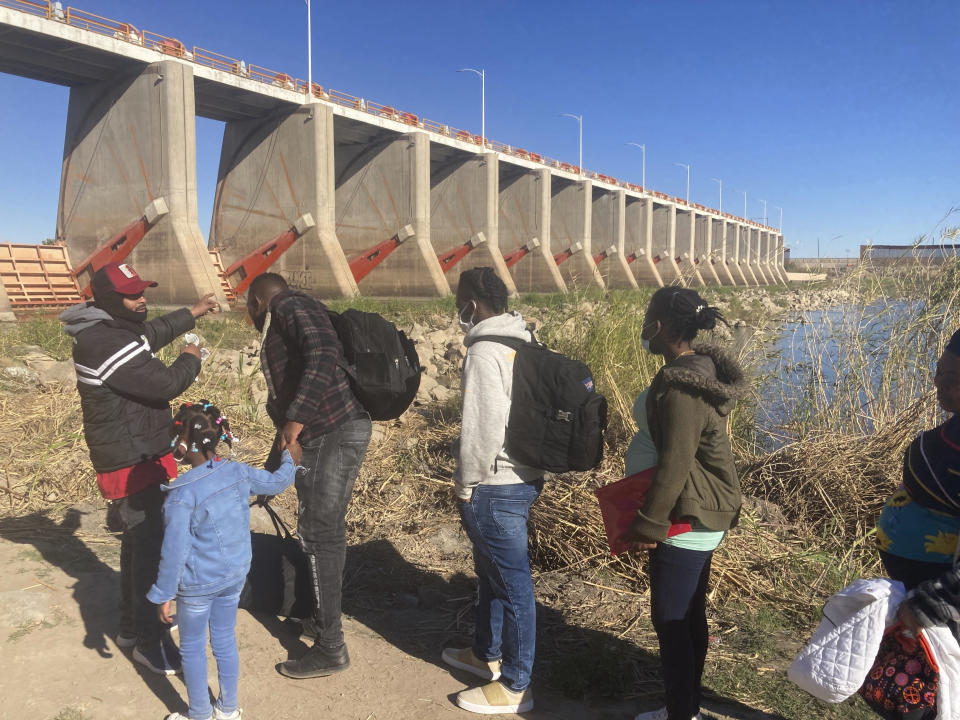 HOLD FOR STORY BY ELLIOT SPAGAT — A Mexican smuggler guides a Haitian family across the Morelos Dam over the Colorado River from Los Algodones, Mexico, on Friday, Feb. 4, 2022, to Yuma, Ariz., on the other side. For nationalities that don't need a visa, Mexico is often the ticket to seeking asylum in the United States. (AP Photo/Elliot Spagat)