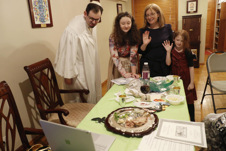 Rabbi Shlomo Segal, left, and his family wave goodbye to participants after he conducted a virtual Passover seder for members of his congregation, friends and family and broadcast it on YouTube and internet dial-in connections from his home in the Sheepshead Bay section of Brooklyn during the current coronavirus outbreak, Wednesday, April 8, 2020, in New York. From left, are Segal, daughter Shira, 12, wife Adina and daughter Rayna, 8. (AP Photo/Kathy Willens)