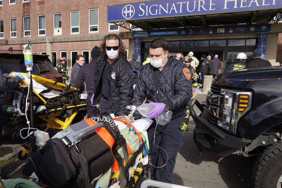 A patient, below center, is evacuated from Signature Healthcare Brockton Hospital, Tuesday, Feb. 7, 2023, in Brockton, Mass. A fire at the hospital's electrical transformer forced an undetermined number of evacuations Tuesday morning and power was shut off to the building for safety reasons, officials said. (AP Photo/Steven Senne)