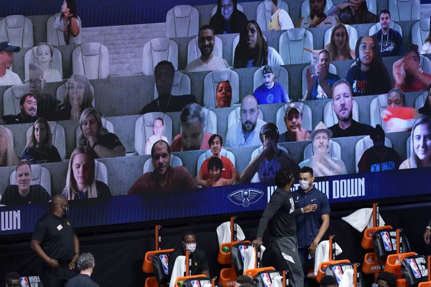 Photos of fans are seen on screens during the second half of an NBA basketball game between the New Orleans Pelicans and the Utah Jazz Thursday, July 30, 2020, in Lake Buena Vista, Fla. (AP Photo/Ashley Landis, Pool)