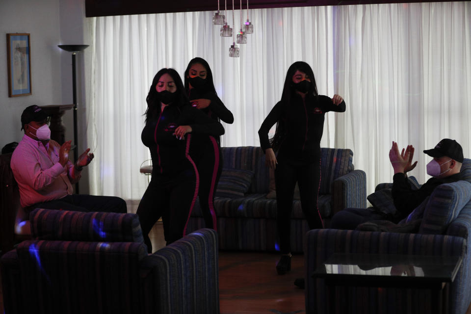 Women wearing protective face masks amid the new coronavirus pandemic, dance in a client's home in Mexico City, Saturday, Aug. 8, 2020. The pandemic has forced business to adapt to a new normality and the adult entertainment industry is no exception. After three months of inactivity, Mi Ultimo Beso relaunched its table-dance-at-home service observing health measures. (AP Photo/Eduardo Verdugo)