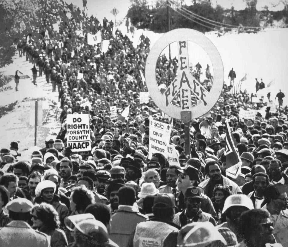 Participants, carrying signs reading Peace and Do Right Forsyth County, make their way to Cumming for the 1987 civil rights march.