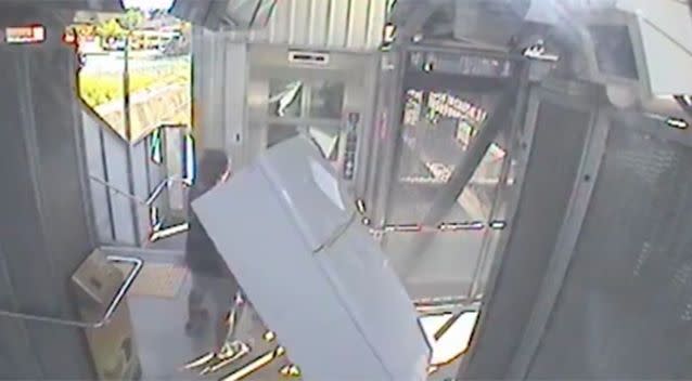 The man attempts to put the fridge in the lift. Photo: Facebook / Queensland Rail