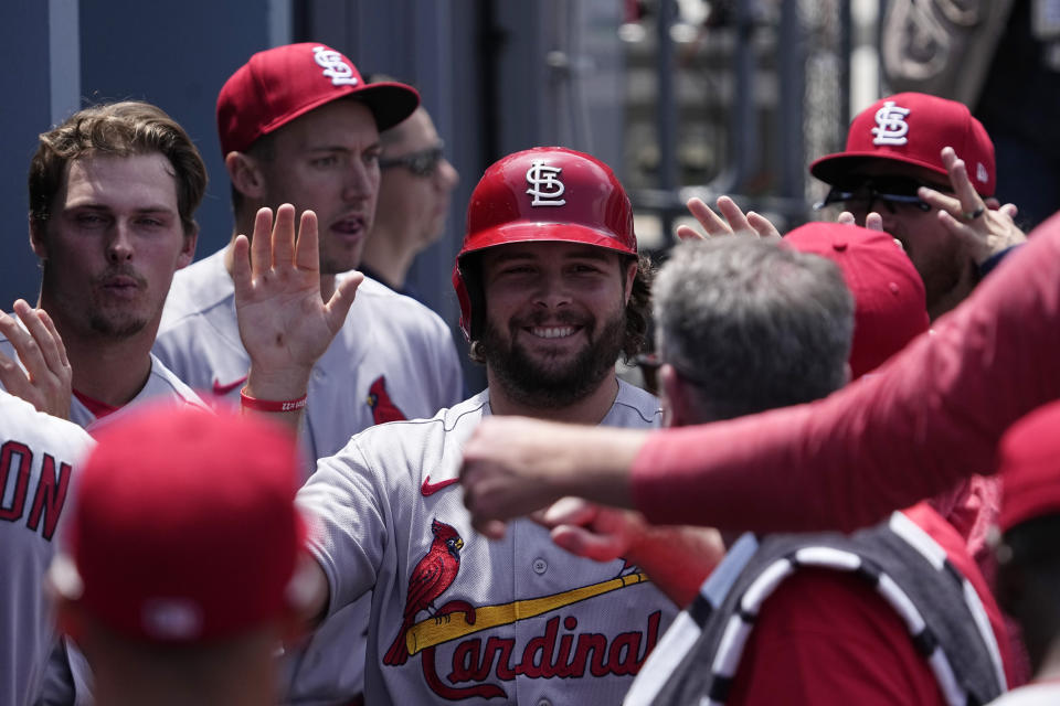 St. Louis Cardinals' Alec Burleson is congratulated by teammates in the dugout after scoring on a single by Brendan Donovan during the second inning of a baseball game against the Los Angeles Dodgers Sunday, April 30, 2023, in Los Angeles. (AP Photo/Mark J. Terrill)