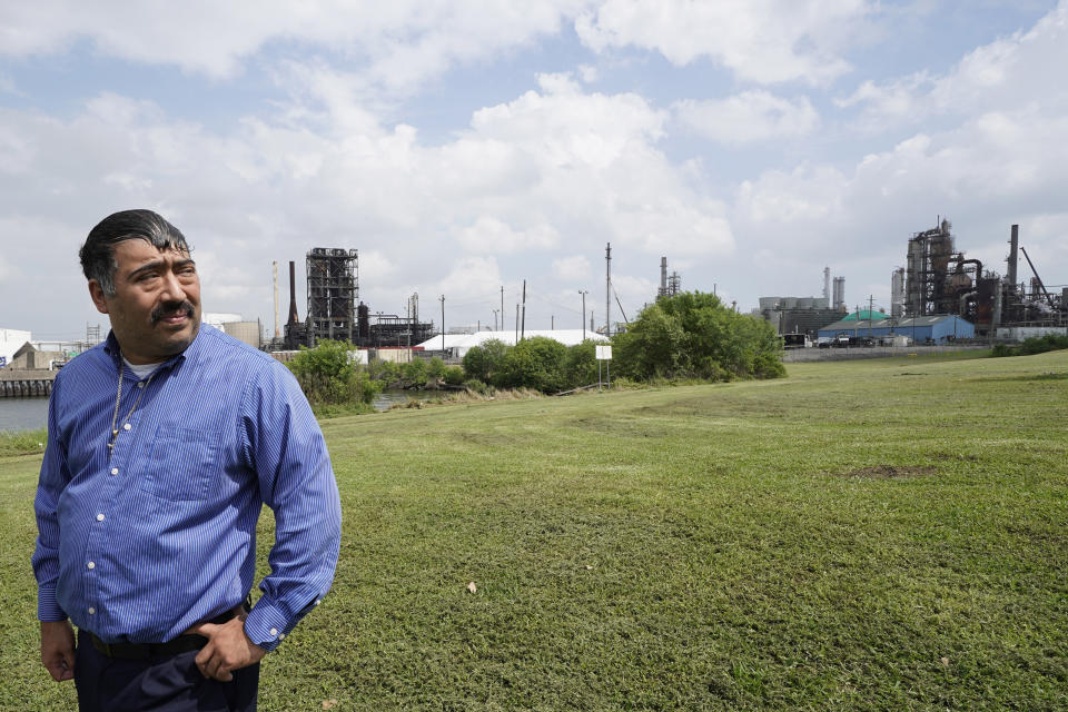 FILE - In this Monday, March 23, 2020 file photo, Juan Flores stands in small park near a refinery along the Houston Ship Channel in Houston. Flores is working on a project to install air monitors at schools, not to warn children when the air was too bad to play outside, but alert them when plant emissions were low enough to make that safe. (AP Photo/David J. Phillip)