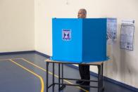 Israeli Prime Minister Benjamin stands behind a voting booth as he votes during Israel's parliamentary election at a polling station in Jerusalem