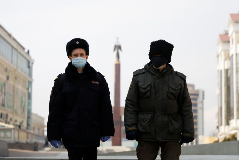 A police officer and a cossack wearing protective masks patrol the territory in Stavropol