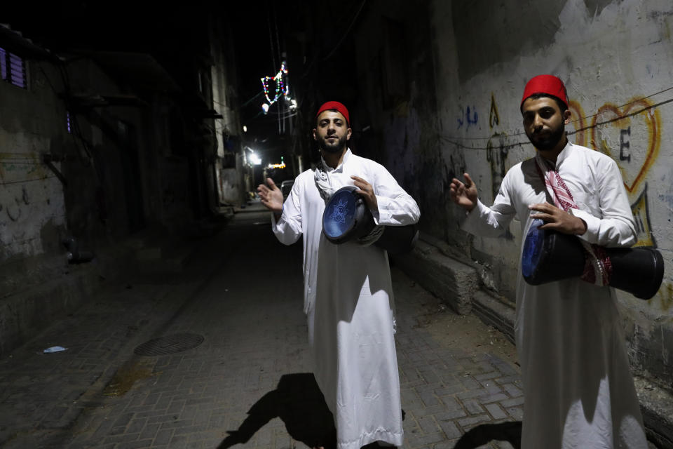 Hamodah Zakout, left, and his brother Ahmad, right, Palestinian awakener, or Al Musaharati in Arabic, beat drums to wake up Muslims for their late night suhur meal before they start the last day fasting of the holy month of Ramadan, along the alleys early Wednesday at Shati refugee camp, in Gaza City, April 21, 2021. Muslims across the world are observing the holy fasting month of Ramadan, where they refrain from eating, drinking and smoking from dawn to dusk. (AP Photo/Adel Hana)