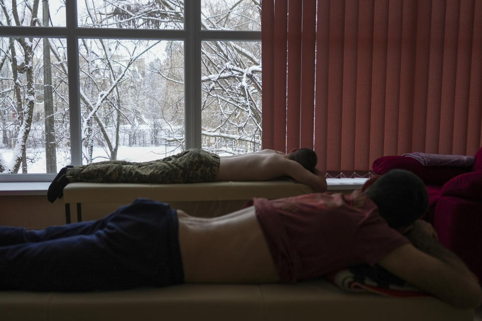 Soldiers lie in a room to receive acupuncture treatment at a clinic which treats veterans for PTSD, post-combat stress and post-concussion trauma, in Kyiv, Ukraine, Monday, Nov. 21, 2022. When peace returns to Ukraine, many thousands of its combatants will likely return with psychological scars from the battlefields. A mental health rehabilitation center for soldiers on the outskirts of Ukraine's capital, Kyiv, treats post-traumatic disorders with acupuncture, soothing sounds and other therapies. (AP Photo/John Leicester)