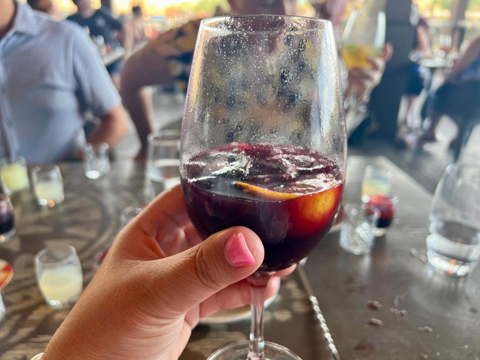 Author holding glass half-filled with dark red sangria.