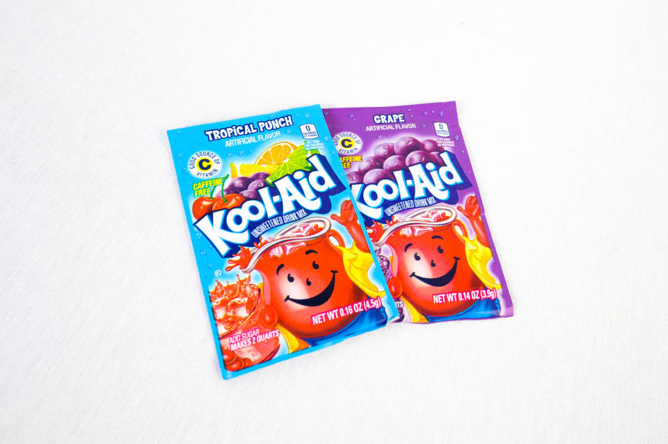 Kool-Aid packets featuring Tropical Punch and Grape flavors are displayed side by side. Both packets showcase the Kool-Aid Man mascot and fruit images