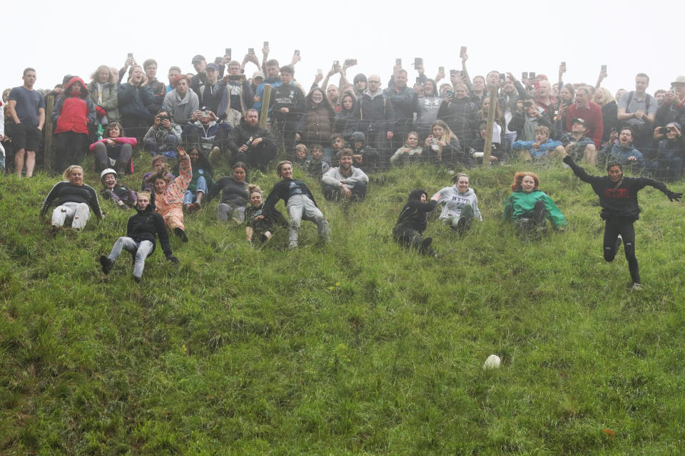 GLOUCESTER, ENGLAND - JUNE 05: Contestants in the women's downhill race chase the cheese down the hill race during Gloucestershire's famous Cheese-Rolling contest on June 05, 2022 in Gloucester, England. The Cooper's Hill Cheese-Rolling and Wake annual event returns this year after a break during the Covid pandemic. It is held on the Spring Bank Holiday at Cooper's Hill, near Gloucester and this year it happens to coincide with the Queen's Platinum Jubilee. Participants race down the 200-yard-long hill after a 3.6kg round of Double Gloucester cheese. (Photo by Cameron Smith/Getty Images)