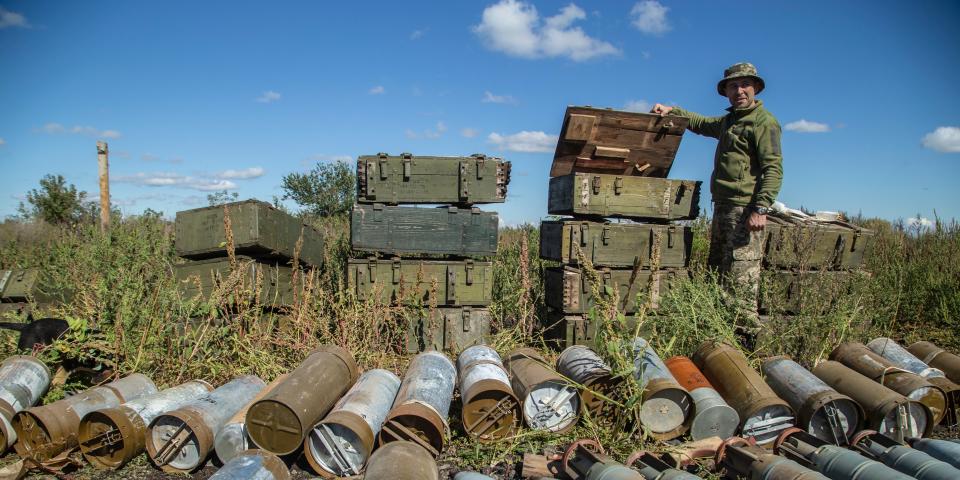 A Ukrainian soldier stands among ammunition.