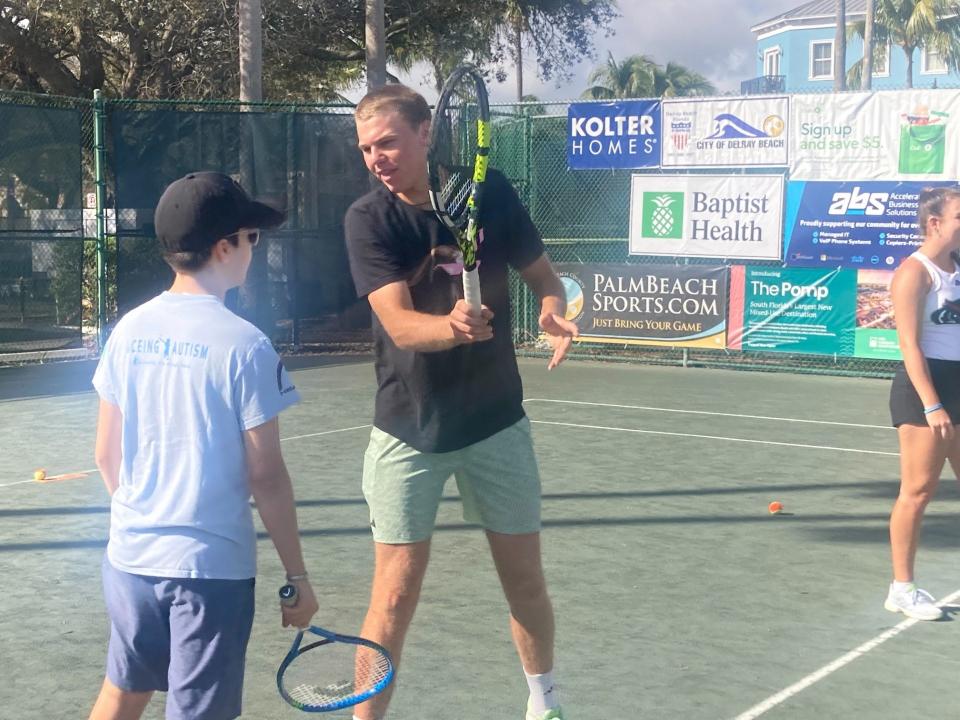 Alex Michelsen works with one of the tennis campers taking part in “ACEing Autism” Sunday morning at the Delray Beach Tennis Center.