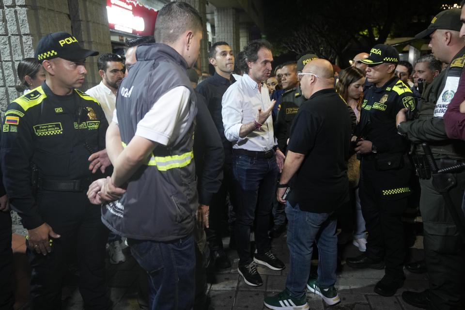 The Mayor of Medellin, Federico Gutierrez, center, talks with one of his municipal workers as he visits police patrolling Lleras Park to enforce a curfew on minors in Medellin, Colombia, Friday, Feb. 2, 2024. A tourism boom in Medellin has presented officials with a new set of challenges, including an uptick in sex trafficking and the killing of tourists and Colombian women after rendezvous on dating apps. (AP Photo/Fernando Vergara)