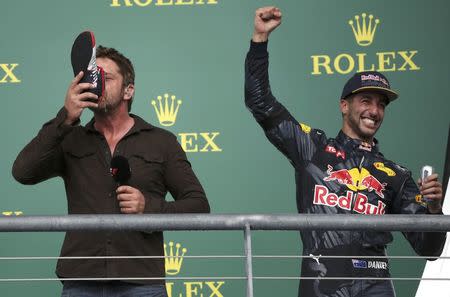 Formula One F1 - U.S. Grand Prix - Circuit of the Americas, Austin, Texas, U.S., 23/10/16. Third placed finisher Red Bull driver Daniel Ricciardo of Australia celebrates as actor Gerard Butler drinks Red Bull from Ricciardo's racing shoe during the ceremony after the race. REUTERS/Adrees Latif