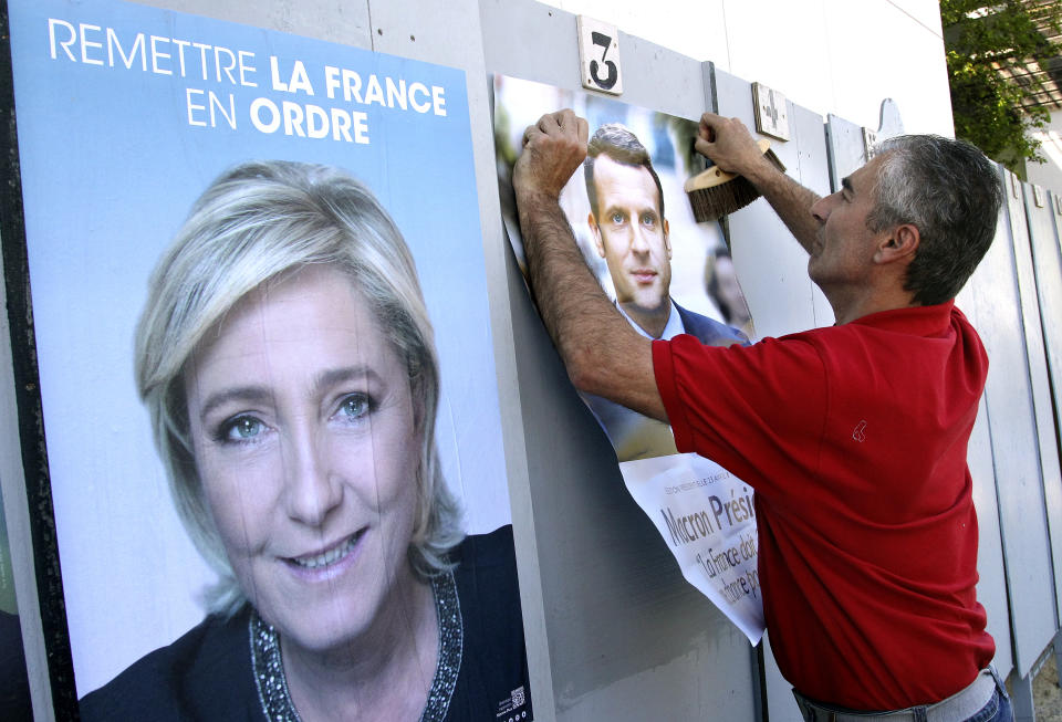 A centrist Macron supporter affixes a poster next to an poster for far-right Marine Le Pen in southwestern France. Source: AP