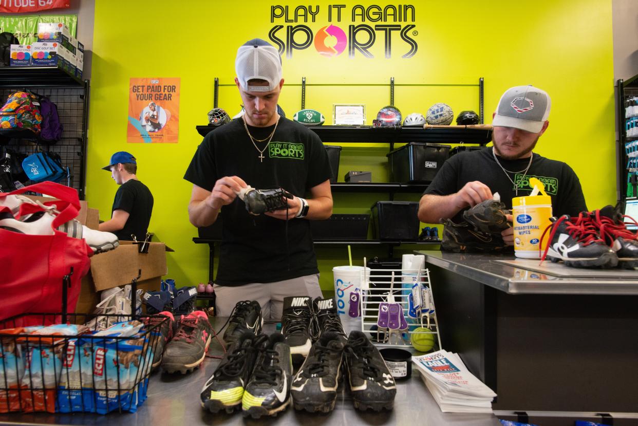 Play It Again Sports employees Cal Leonard, left, and Andrew Schmidtlein clean pairs of used football and baseball cleats a customer sold them Tuesday.