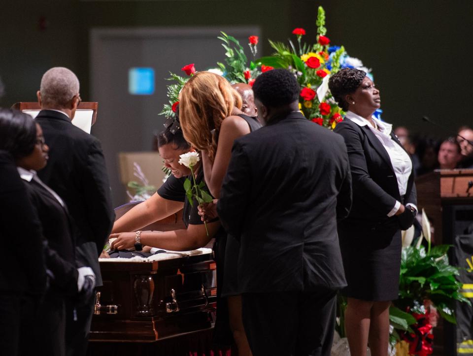 Daughters Gerrica and Mary Gerallisa Bates lay flowers on their father, veteran firefighter Gerald Bates, at New Horizon Church International in Jackson, Miss, on Saturday, April 20, 2024.