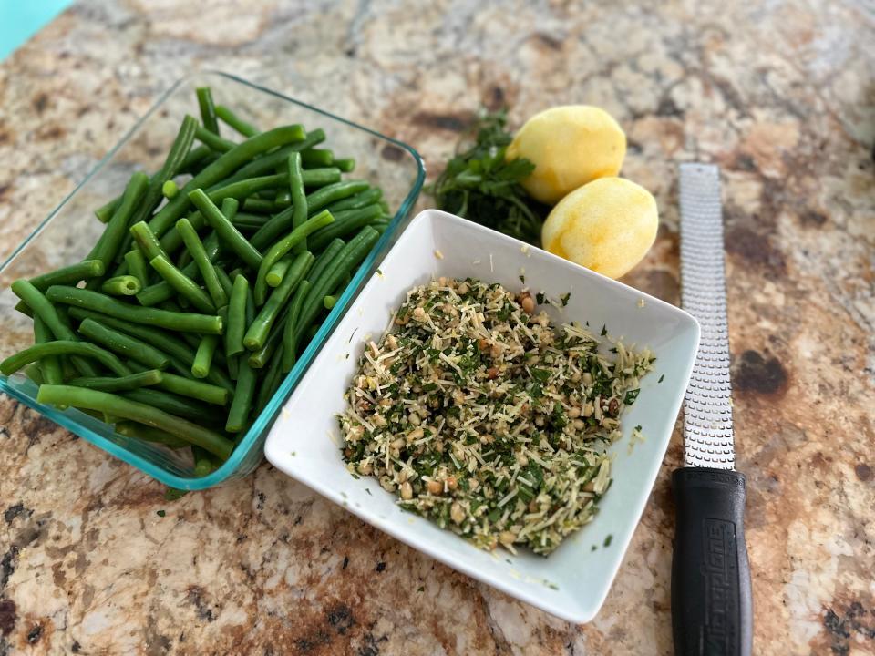 Green beans next to bread crumb mixture next to lemon zester on counter