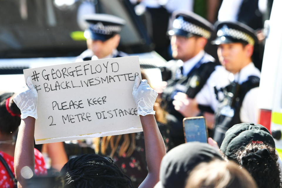 A demonstrator holds up a sign reminding people to social distance during a Black Lives Matter protest outside the US Embassy in London. The protest follows the death of George Floyd in Minneapolis, US, this week which has seen a police officer charged with third-degree murder. (Photo by Dominic Lipinski/PA Images via Getty Images)