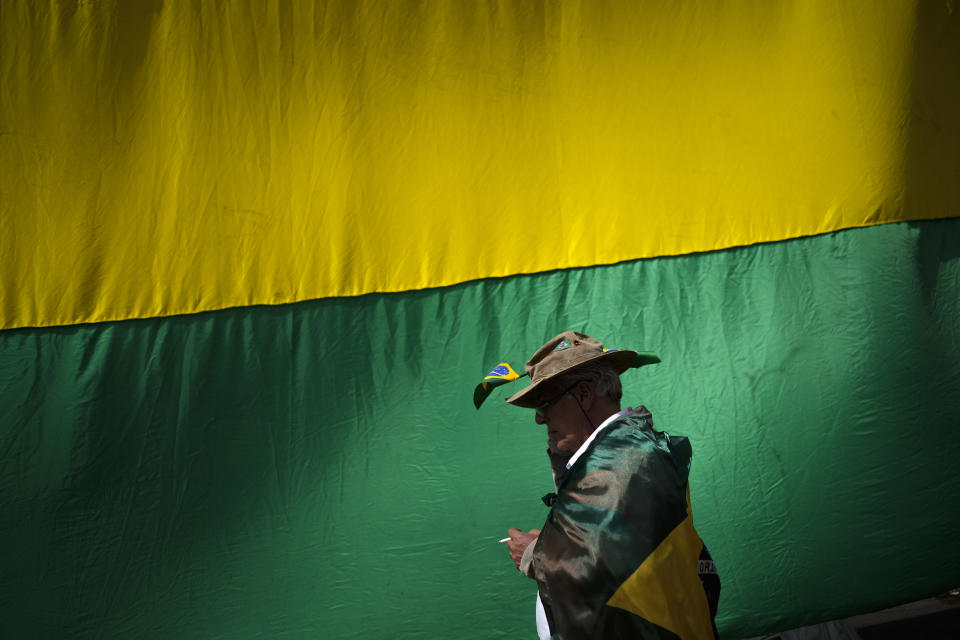 A supporter of Brazilian President Jair Bolsonaro walks past a giant national flag during a protest against his defeat in the country's presidential runoff, outside a military base in Sao Paulo, Brazil, Thursday, Nov. 3, 2022. Some supporters are calling on the military to keep Bolsonaro in power, even as his administration signaled a willingness to hand over the reins to his rival, President-elect Luiz Inacio Lula da Silva. (AP Photo/Matias Delacroix)