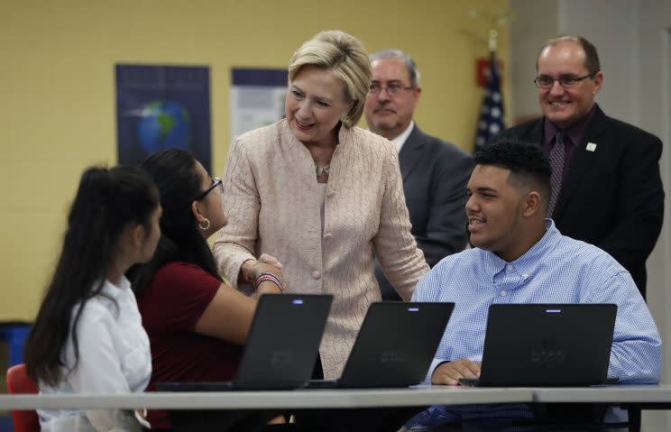 Democratic presidential candidate Hillary Clinton talks with students at John Marshall High School in Cleveland in August. (Photo: Carolyn Kaster/ AP. Illustration below: Getty Images)