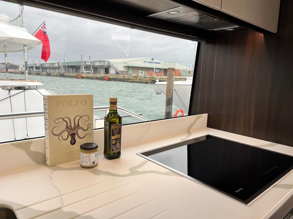 A bottle of olive oil and a cooking book next to a conduction hob onboard a Sunseeker 76