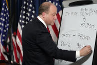 Colorado Gov. Jared Polis uses a board to write down the doses of coronavirus vaccine expected by the state to check the spread of the coronavirus pandemic at a news conference Friday, Jan. 15, 2021, in Denver. (AP Photo/David Zalubowski)