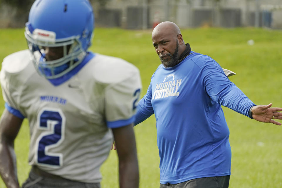 Murrah High School football coach Marcus Gibson encourages his quarterback Odarrius Harris (2) during practice, Wednesday, Aug. 31, 2022, in Jackson, Miss. The city's low water pressure concerns Gibson, limiting his options for washing practice uniforms, towels and other gear his players wear. The recent flood worsened Jackson's longstanding water system problems and the state Health Department has had Mississippi's capital city under a boil-water notice since late July. (AP Photo/Rogelio V. Solis)