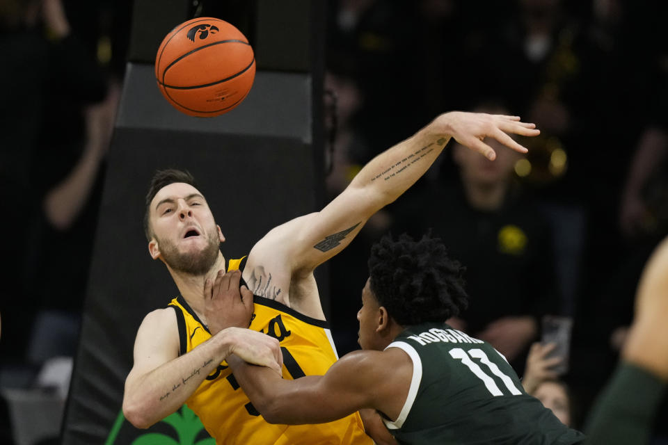 Iowa guard Connor McCaffery, left, fouls Michigan State guard A.J. Hoggard (11) during overtime in an NCAA college basketball game, Saturday, Feb. 25, 2023, in Iowa City, Iowa. Iowa won 112-106 in overtime. (AP Photo/Charlie Neibergall)