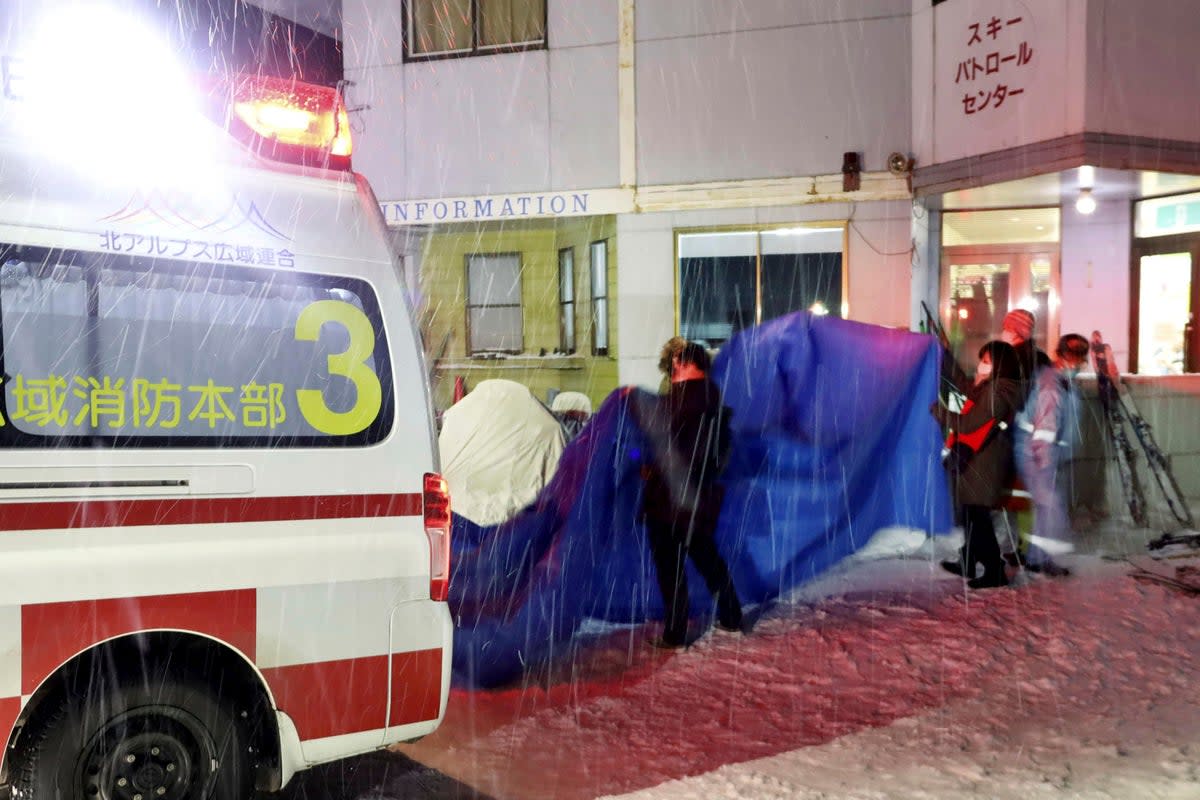 Injured skiers, behind a blue sheet, get into an ambulance at a ski resort in the village of Otari, Nagano prefecture, Japan Sunday, Jan. 29, 2023 (AP)