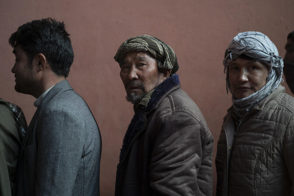 People wait in a line to receive cash at a money distribution organized by the World Food Program (WFP) in Kabul, Afghanistan, Wednesday, Nov. 3, 2021. Afghanistan's economy is fast approaching the brink and is faced with harrowing predictions of growing poverty and hunger. (AP Photo/Bram Janssen)