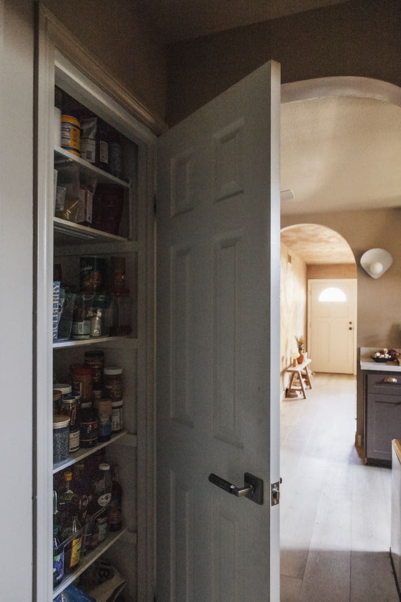 Pantry closet open and view into the kitchen and entryway