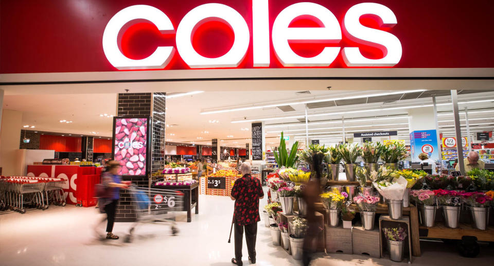 Coles shoppers walking into Coles supermarket with flowers at entrance