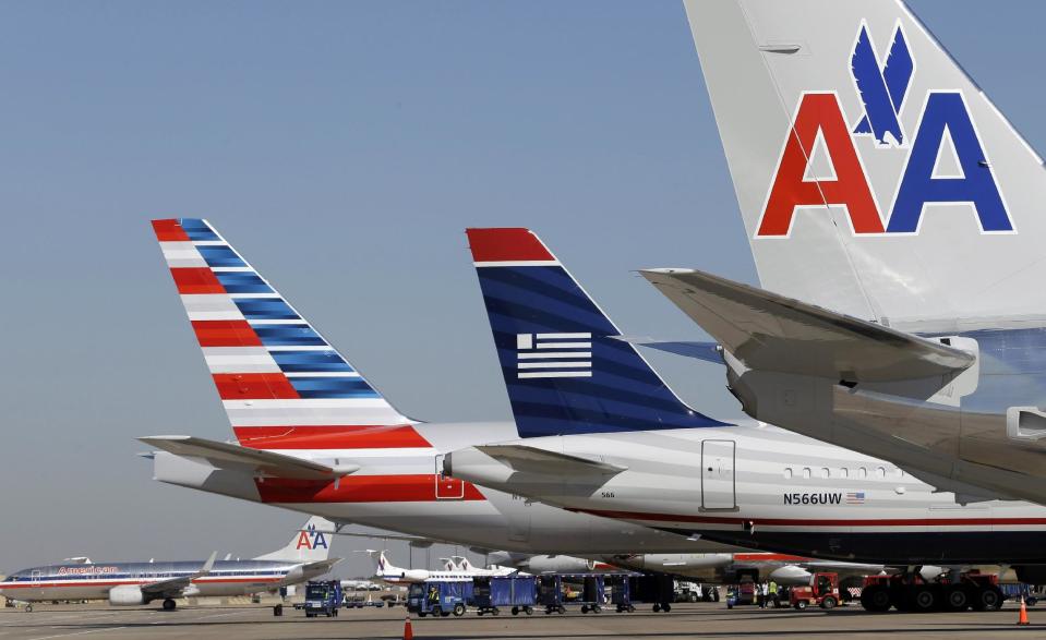 FILE - In this Thursday, Feb. 14, 2013 file photo, U.S. Airways and American Airlines planes are shown at gates at DFW International Airport in Grapevine, Texas. The new American Airlines will have more top executives from smaller US Airways than from the current American. The companies named eight senior executives on Monday, June 10, 2013, including five from US Airways and three from American parent AMR Corp. AMR and US Airways Group Inc. hope to complete their proposed merger this summer. (AP Photo/LM Otero, File)