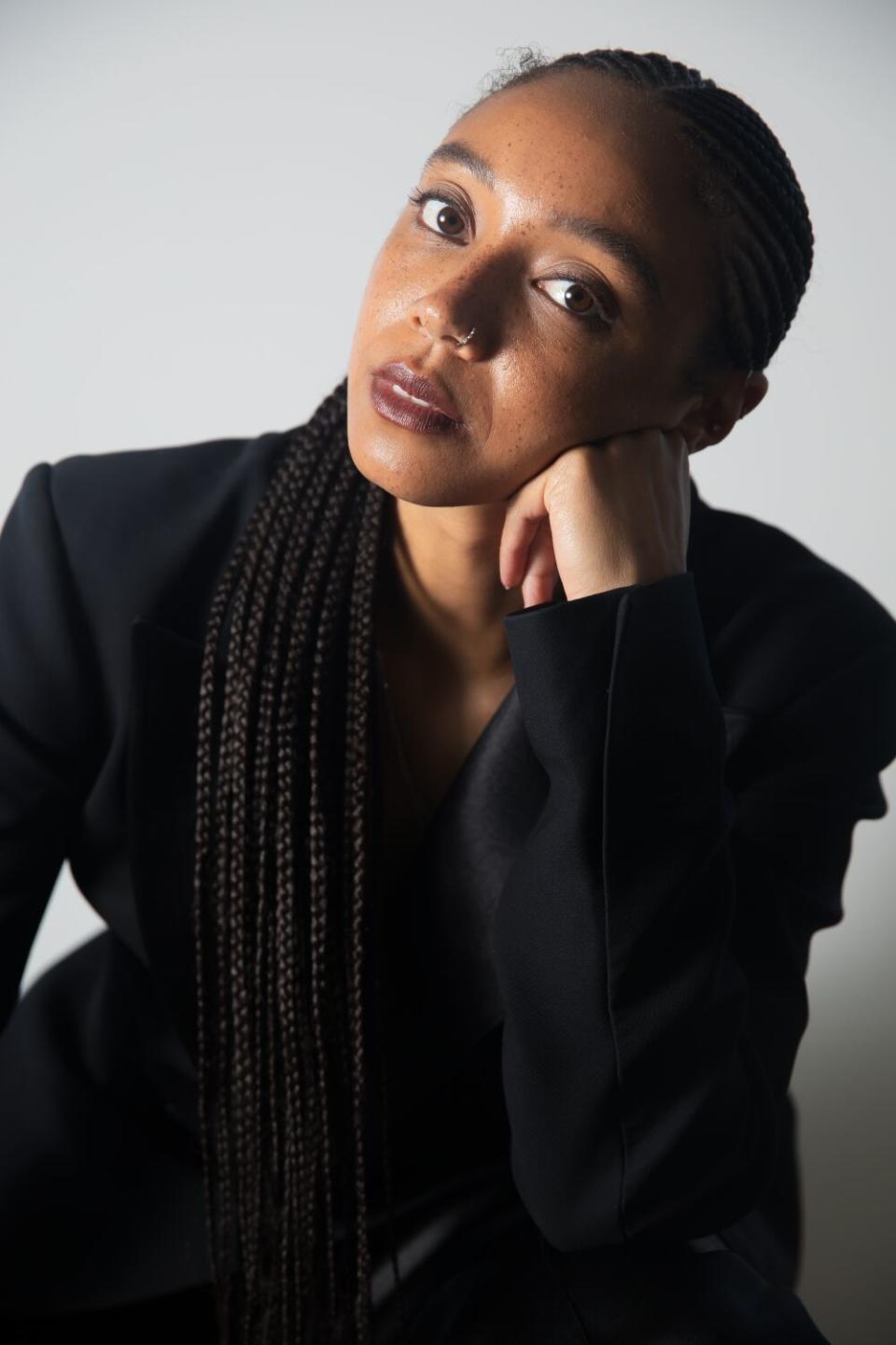 A woman dressed in black leans her head on her hand.