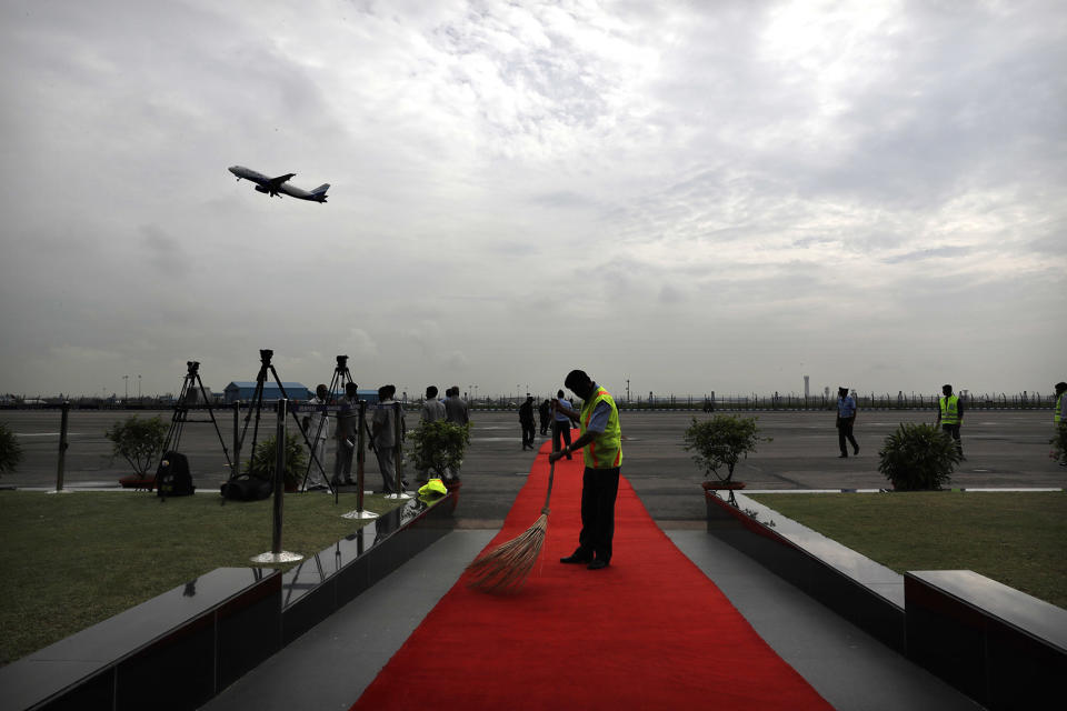 A worker sweeps red carpet before the arrival of Egyptian President Abdel-Fattah el-Sissi in New Delhi, India