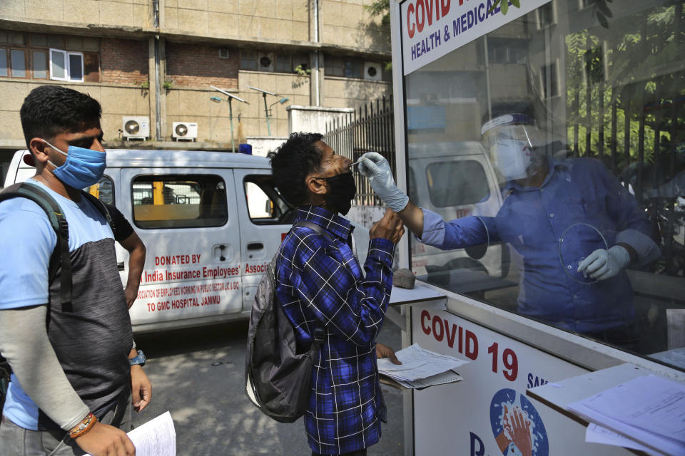 A health worker collects a man's swab sample to test for COVID-19 at a government hospital in Jammu, India, Thursday, Oct.1, 2020. India is expected to become the pandemic's worst-hit country within weeks, surpassing the United States. (AP Photo/Channi Anand)