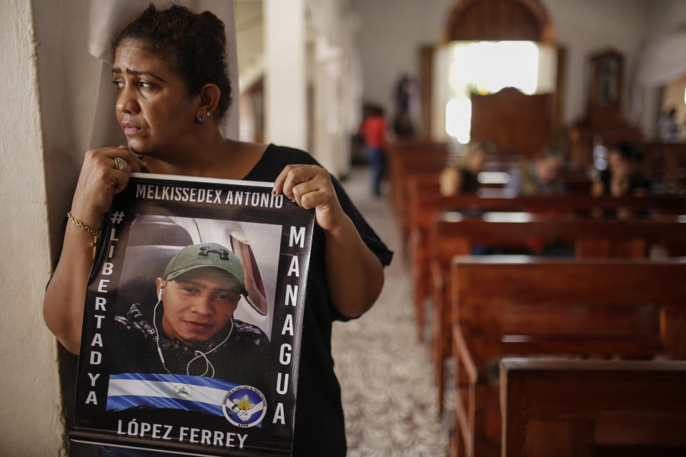 Martha Lorena Alvarado, mother of jailed anti-government demonstrator Melkkisedex Antonio Lopez, holds a sign with an image of her son at the San Miguel Arcangel Church in Masaya, Nicaragua, Thursday, Nov. 14, 2019. Alvarado has joined a hunger strike to demand the freedom of their relatives, jailed for protesting against the government of President Daniel Ortega. (AP Photo/Alfredo Zuniga)