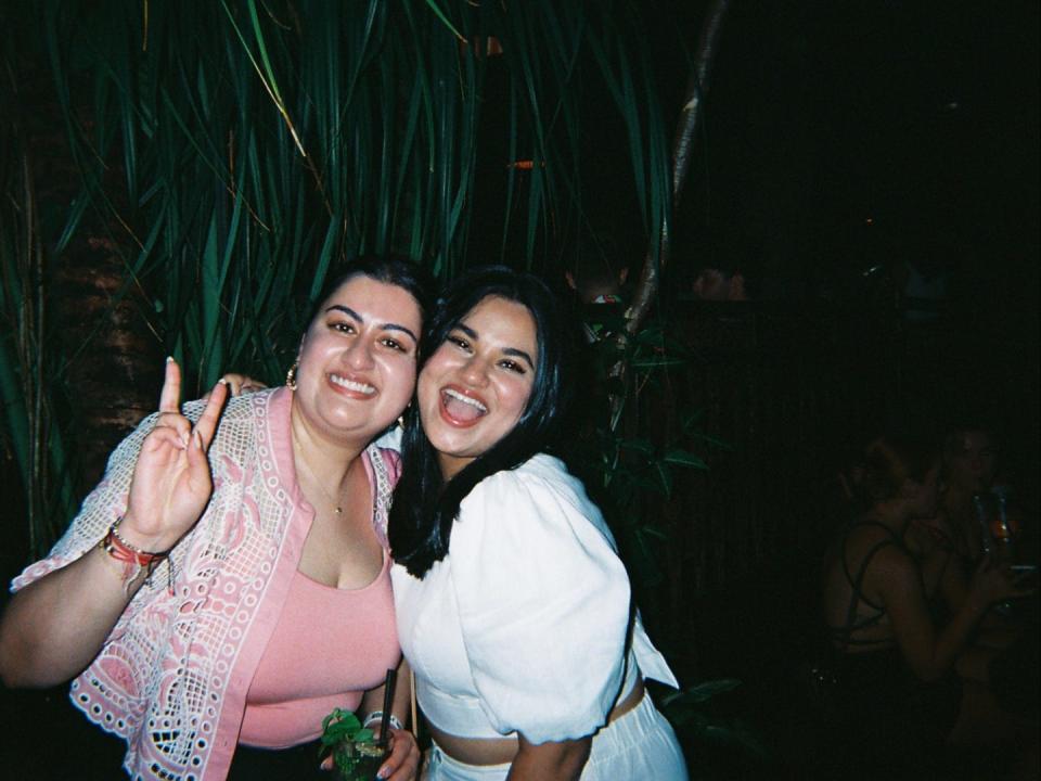 Two girls posing at La Favela in Seminyak, Bali - the one on the left has two fingers up in a "peace" sign whereas the other is smiling.