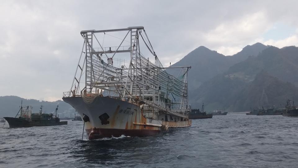 Large fishing boats near mountains.