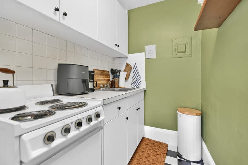 White cabinets with tile back splash with green accent wall.