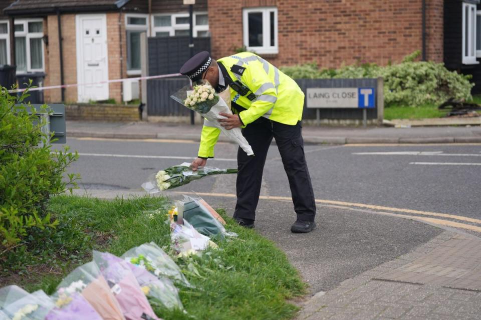 A police officer lays flowers at the scene (Yui Mok/PA Wire)