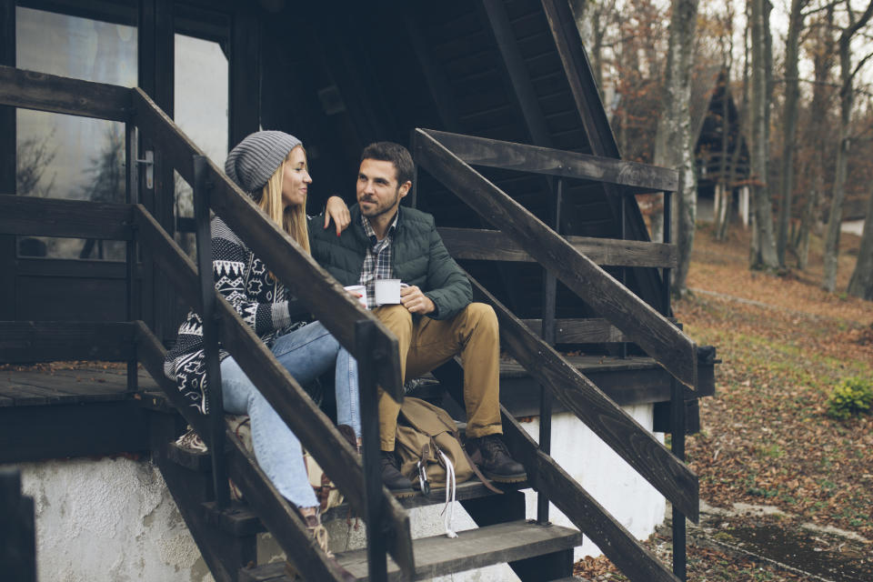 Pictured: Couple drinking tea outside a cozy house. Living rurally lowers your risk of developing Alzheimer's. Image: Getty