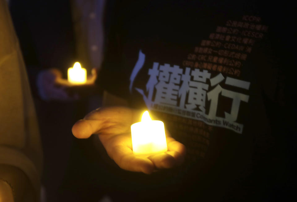 A participant holds a candle with a slogan reading ''Rampant Human Rights'' during a candlelight vigil at Democracy Square in Taipei, Taiwan, Tuesday, June 4, 2024, to mark the 35th anniversary of the Chinese military crackdown on the pro-democracy movement in Beijing's Tiananmen Square. (AP Photo/Chiang Ying-ying)