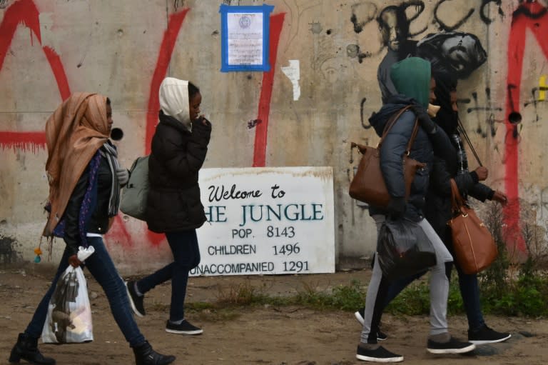 Migrants carry their belongings as they leave the "Jungle" camp in Calais, northern France, on October 24, 2016