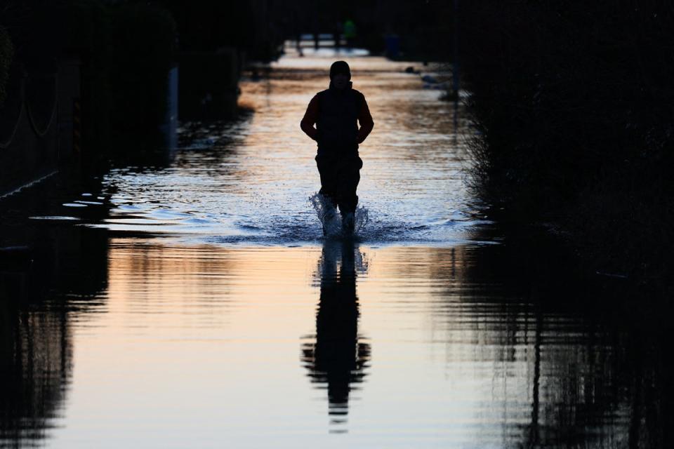 People walk through floodwater on a flooded street in Wraysbury, west of London on January 9, 2024 (AFP via Getty Images)
